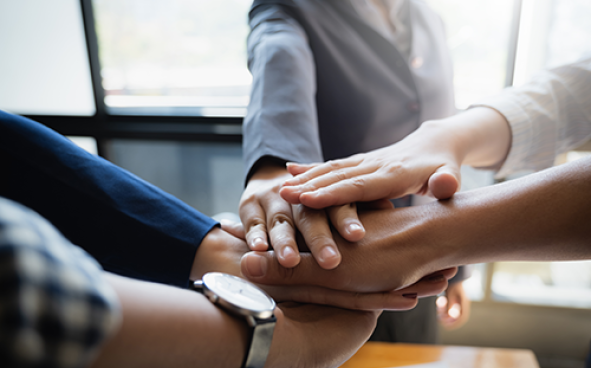 Group of people putting their hands working together in an office.