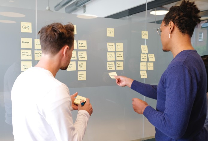 Two people using sticky notes on a wall